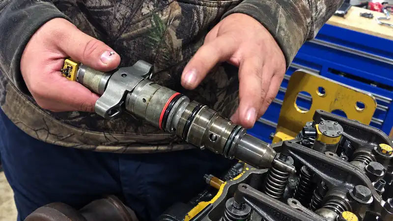 Technician preparing a heavy-equipment common rail engine for clean injector removal